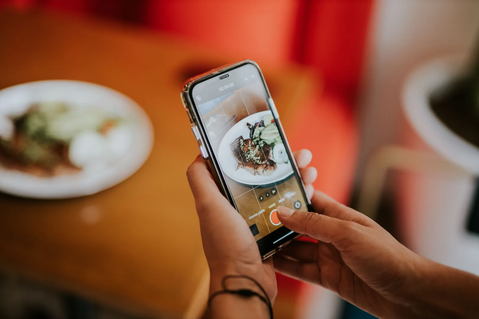 Personne photographiant une assiette avec son smartphone dans un restaurant, pour les réseaux sociaux.