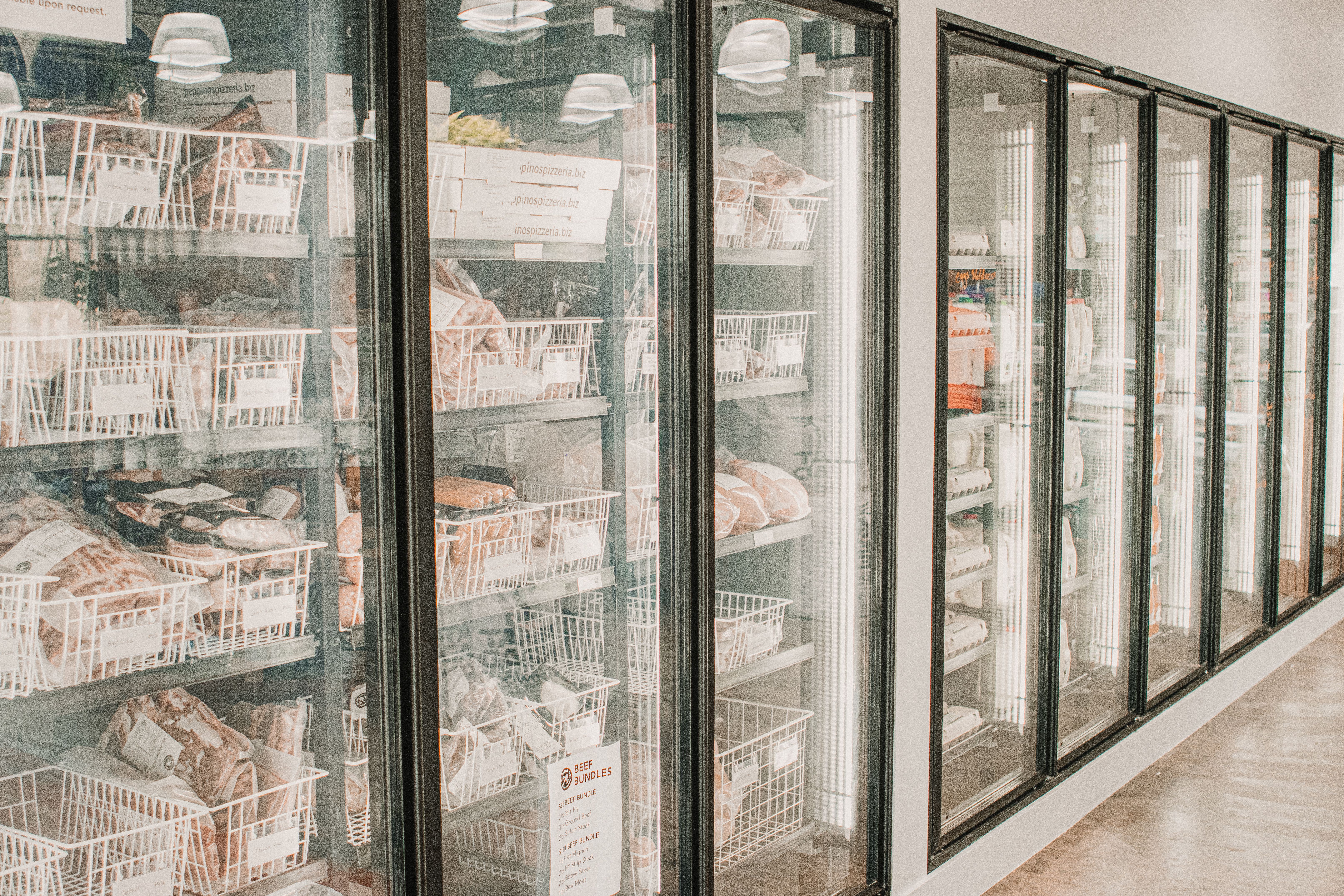 Vitrines réfrigérées garnies de bacs de viande et de produits emballés dans une chambre froide professionnelle.